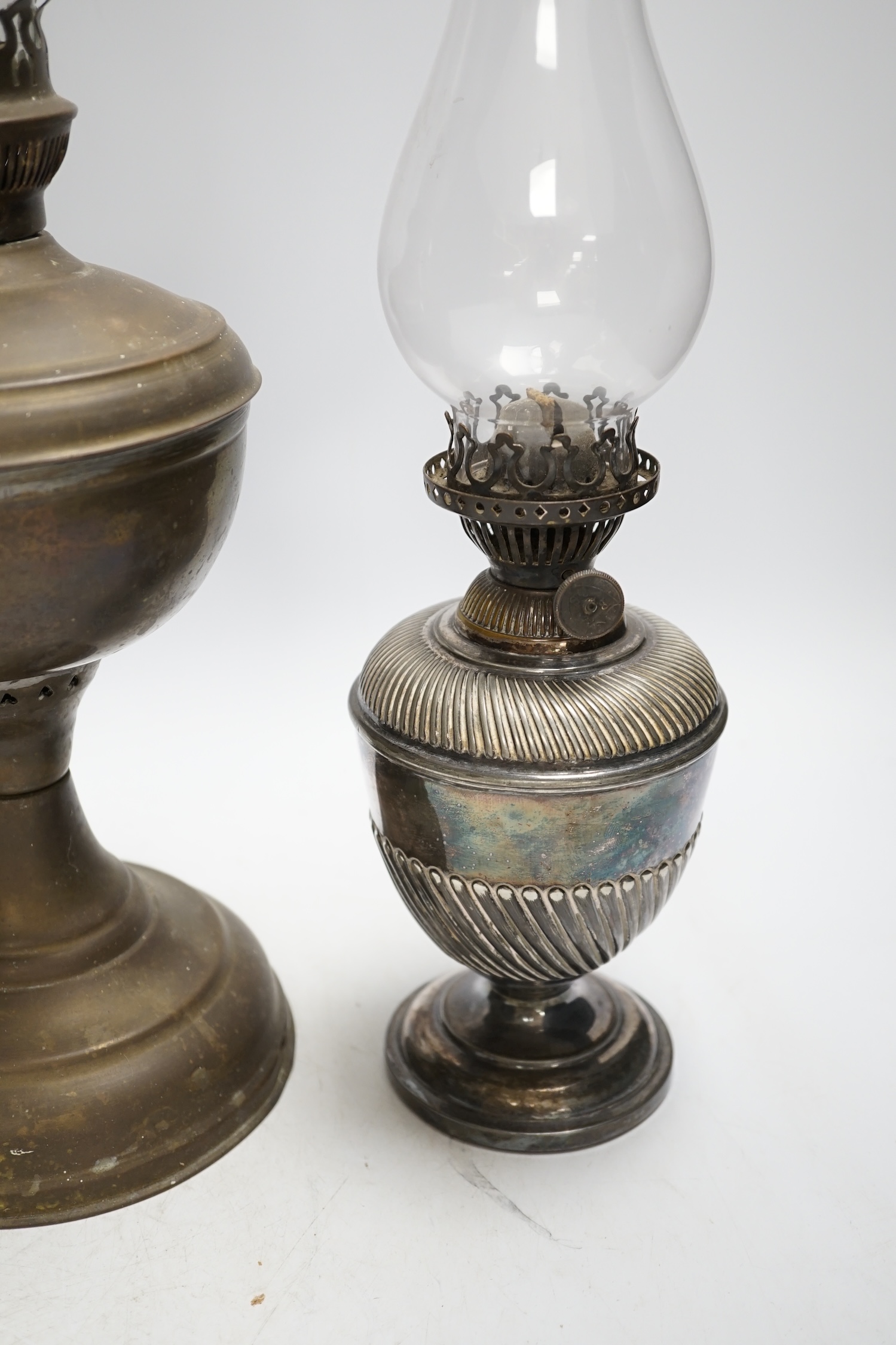 A brass oil lamp and a smaller pair of silver plated oil lamps with glass funnels, tallest including funnel 54cm high. Condition - fair